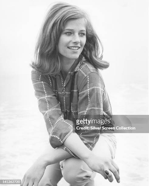 Charlotte Rampling, British actress, crouching for a portrait, wearing a dark blouse with a white dot check pattern, circa 1970