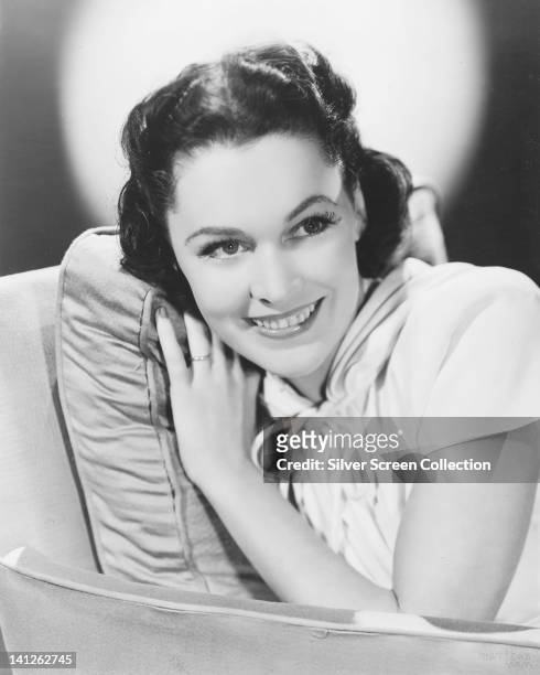 Maureen OSullivan , Irish actress, wearing a white short-sleeve top with a draw string bow at the neck, smiling with her head resting on a cushion...