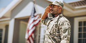 Patriotic young soldier saluting outdoors