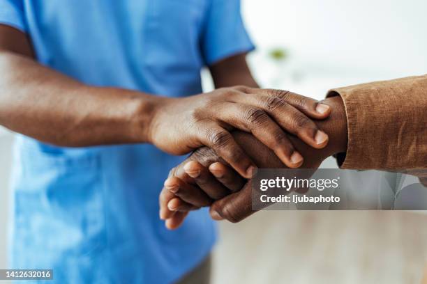 scatto di un infermiere che consola il suo paziente a casa - holding hands close up foto e immagini stock