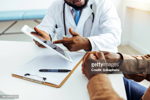 friendly male doctor talks to sick male patient - medicaid stockfoto's en -beelden