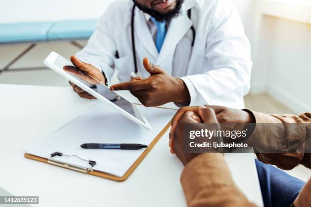 friendly male doctor talks to sick male patient - medicaid stock pictures, royalty-free photos & images