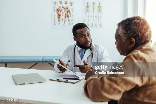 friendly and cheerful family doctor is reading medical history of senior male patient during consultation - doctor and patient talking imagens e fotografias de stock