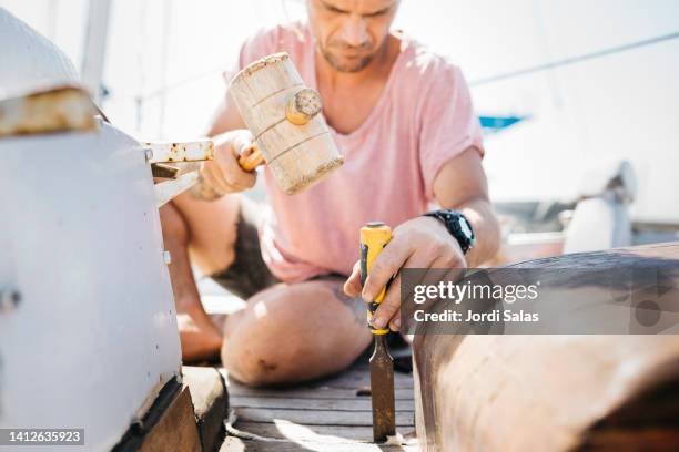 man reconditioning a sailing boat on dry dock - preparazione al parto foto e immagini stock