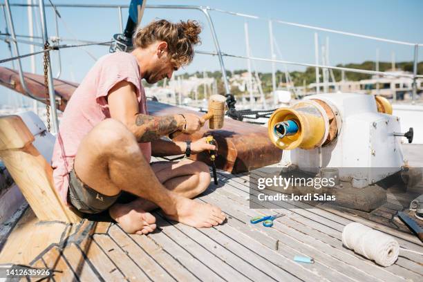 man reconditioning a sailing boat on dry dock - preparazione al parto foto e immagini stock