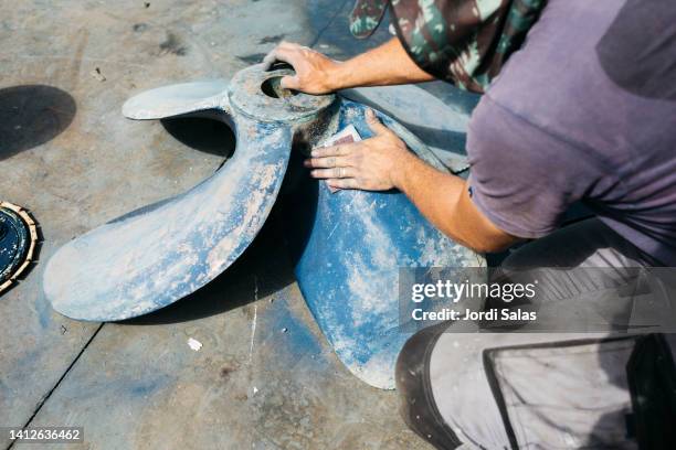 man working on a propeller of a boat - metal sanding stockfoto's en -beelden