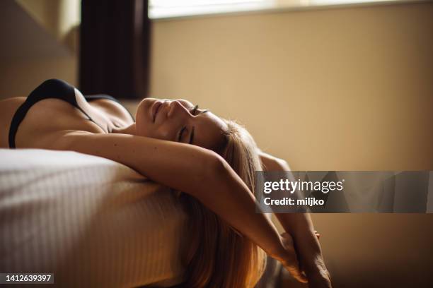 beautiful young woman relaxing in bedroom - bra stock pictures, royalty-free photos & images