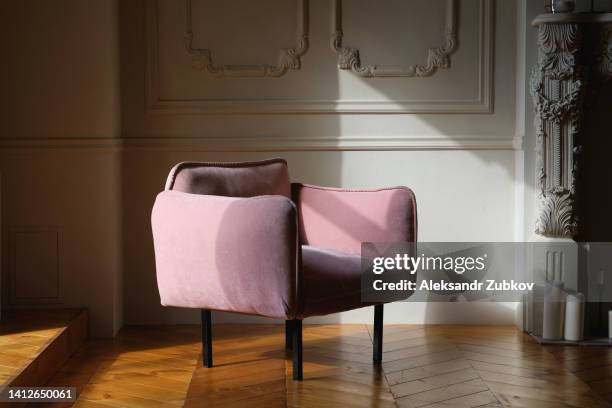 the interior of the living room is made in english style with a pink velour armchair against a light wall, with a wooden floor or parquet. home improvement. beautiful luxurious modern interior. - armchair ストックフォトと画像