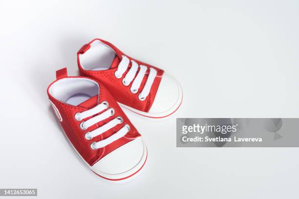 little red booties for newborn babies on white background. - shoelace stock-fotos und bilder