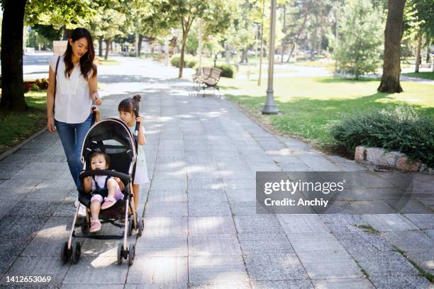 single mom walking in park with baby stroller - mother stroller stock pictures, royalty-free photos & images