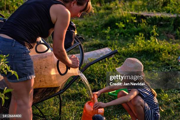 young family preparing to water their field in a communal organic garden - shack stockfoto's en -beelden