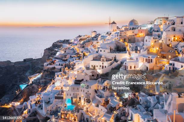 oia, santorini island, cyclades, greece.  cityscape, houses and churches with bell, sea on background - greek culture stock-fotos und bilder