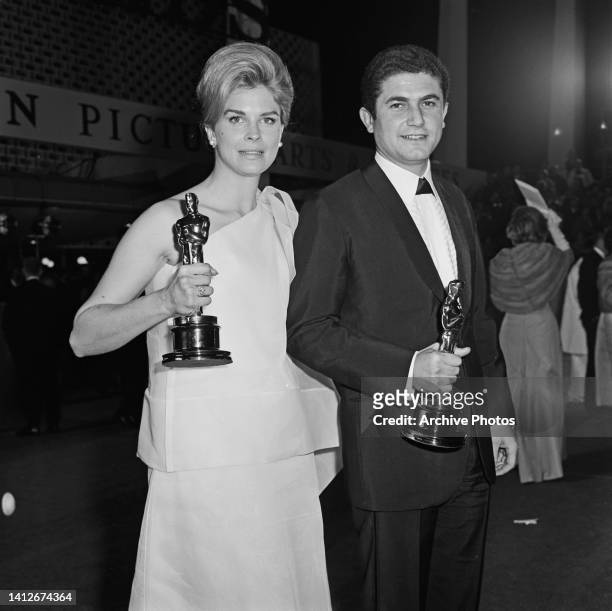 American actress Candice Bergen, wearing a one shoulder evening gown, and French film director Claude Lelouch, wearing a tuxedo, attend the 39th...