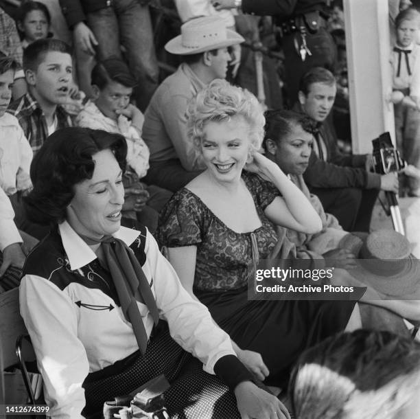 American actress Eileen Heckart and American actress Marilyn Monroe sitting with people in the rodeo scene from the film 'Bus Stop, ' filmed at the...