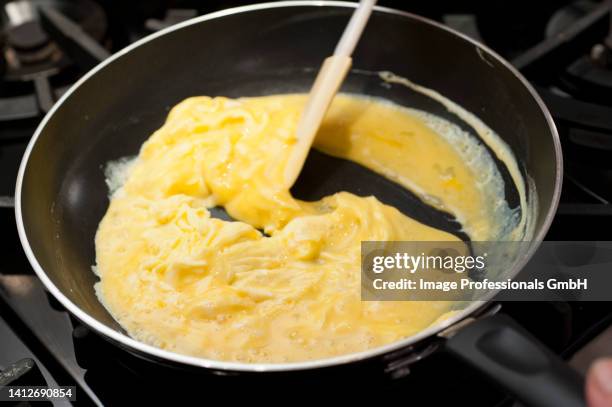 preparing scrambled eggs in a pan - scrambled egg stock pictures, royalty-free photos & images
