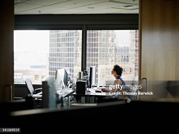 businesswoman sitting in office looking out window - leanincollection foto e immagini stock