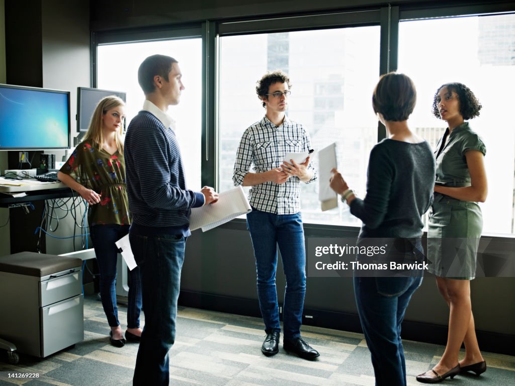 Coworkers standing in discussion in office