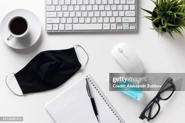 safety and hygiene measures in the office. prevention of the spread of the covid-19 coronavirus epidemic. protective face mask, keyboard, computer mouse, pen and mug with black coffee, hand sanitizer, on the freelancer's desktop or white background. - siberian mouse fotografías e imágenes de stock