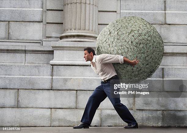 businessman with large ball of money - avidità foto e immagini stock