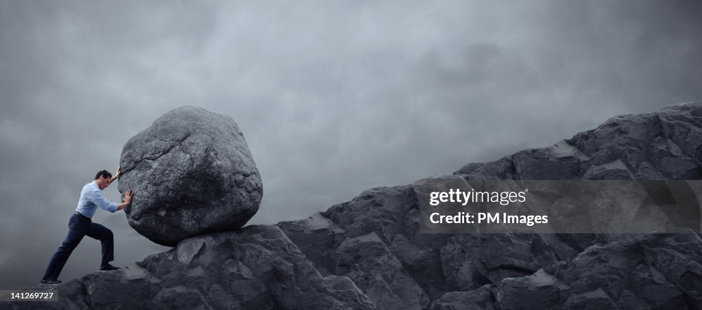 Man rolling rock up hill