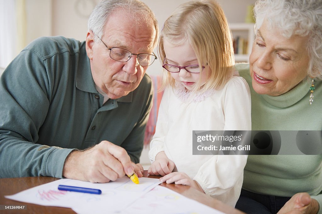 Young girl coloring with grandparents