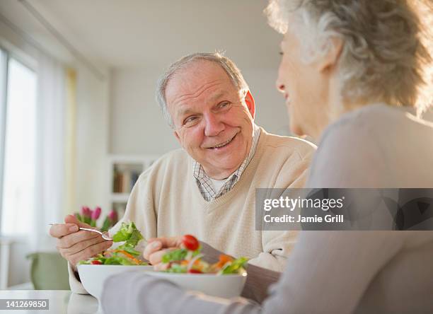 senior couple eating salads together - senior men eating stock pictures, royalty-free photos & images