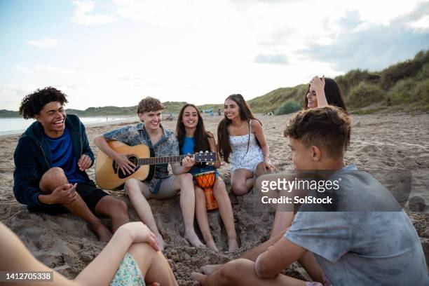 listening to the guitar - young teen girl beach stock pictures, royalty-free photos & images