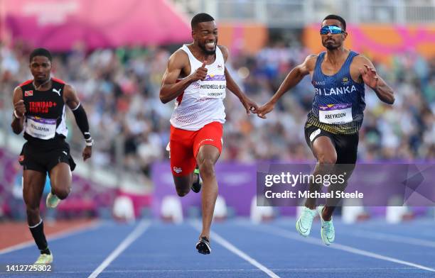 Nethaneel Mitchell-Blake of Team England finishes first alongside Yupun Abeykoon of Team Sri Lanka during the Men's 100m Semi-Finals on day six of...