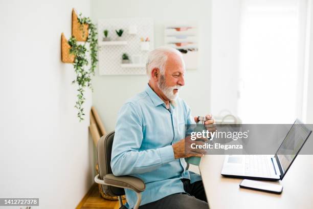 senior man drinking water from reusable bottle at office - reusable water bottle office stock pictures, royalty-free photos & images