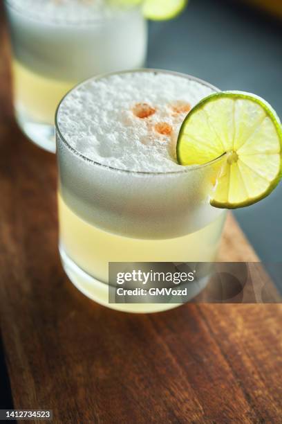 pisco sour cocktail served with lime - pisco sour stockfoto's en -beelden