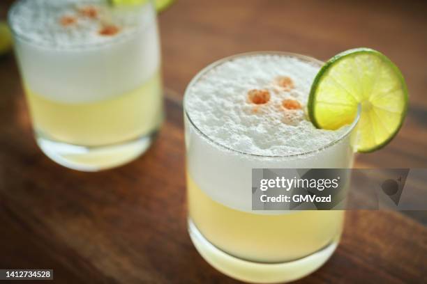 pisco sour cocktail served with lime - pisco sour imagens e fotografias de stock