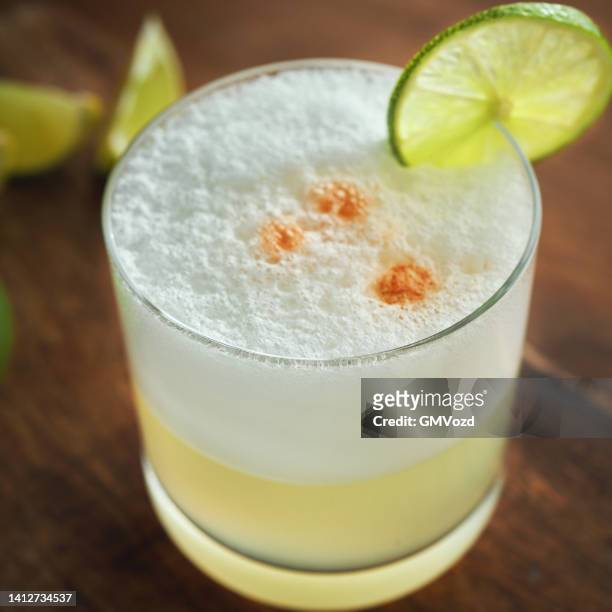 pisco sour cocktail served with lime - pisco sour stockfoto's en -beelden
