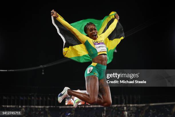 Elaine Thompson-Herah of Team Jamaica celebrates with their countries flag after winning the gold medal in the Women's 100m Final on day six of the...