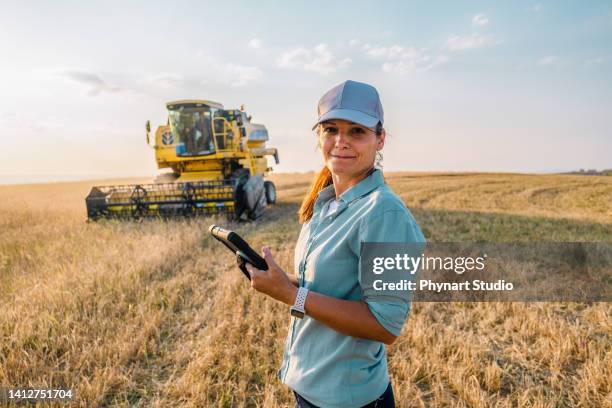 female farmer is holding a digital tablet in a farm field. smart farming - boer-agrarisch-beroep stockfoto's en -beelden