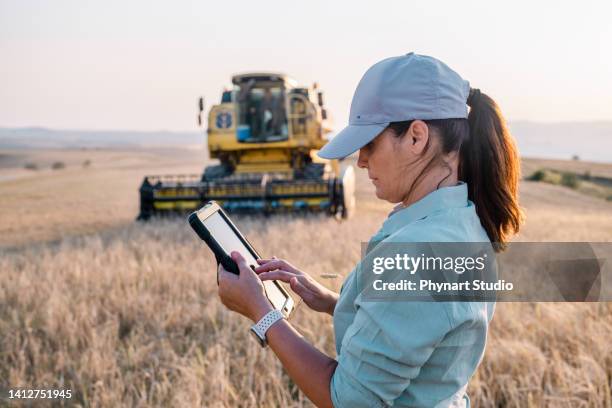 female farmer is holding a digital tablet in a farm field. smart farming - the internet of things stock pictures, royalty-free photos & images