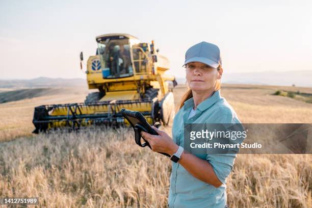 l'agricoltore donna tiene in mano un tablet digitale in un campo agricolo. agricoltura intelligente - farm worker foto e immagini stock
