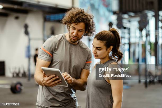 trainer and female client discussing her progress - fitness instructor stock pictures, royalty-free photos & images