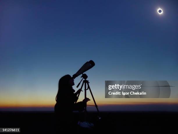 young woman observing total solar eclipse - zonsverduistering stockfoto's en -beelden