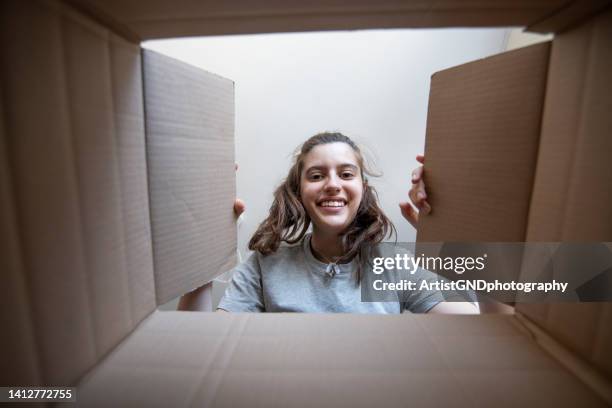 happy young woman looking in delivery box. - opening a box stockfoto's en -beelden