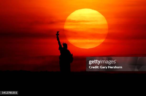 The sun sets behind the Statute of Liberty on August 3 in New York City.