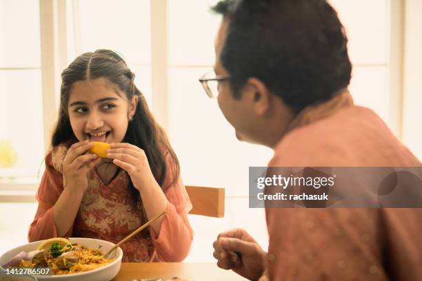 indian girl eating some food by hand - sweet indian home stock pictures, royalty-free photos & images