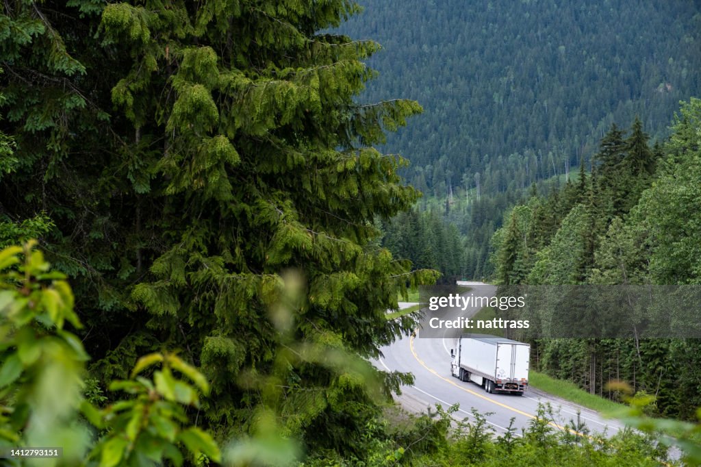 Container-LKW entlang einer malerischen Straße durch die kanadischen Rockies