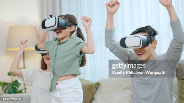 parents and daughters wearing virtual reality glasses play video games. - cardboard vr stock pictures, royalty-free photos & images