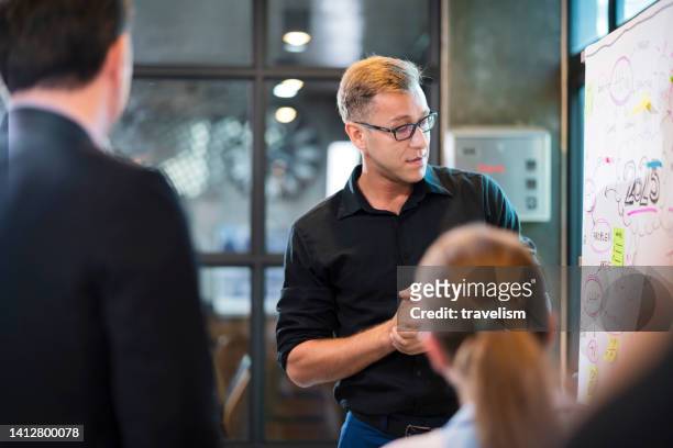 white glasses caucasian male senior business director with young group of professionals developing business strategy and providing the business plan ideas sharing with teamwork together in office - marketing director stock pictures, royalty-free photos & images