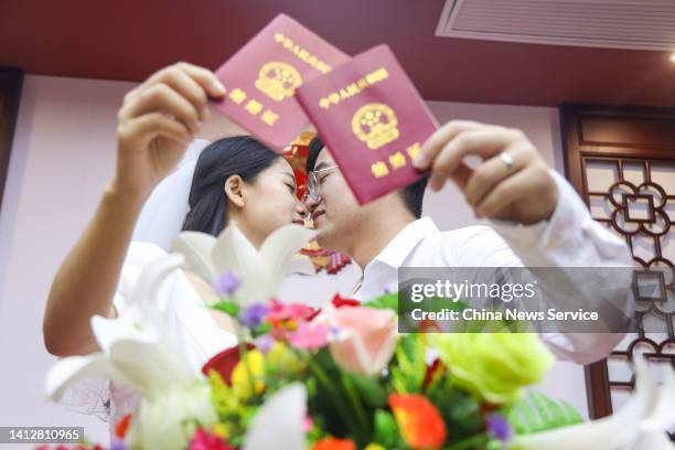 Newlywed couple pose with their marriage certificates at a civil affairs bureau during the Qixi Festival, or Chinese Valentine's Day on August 4,...