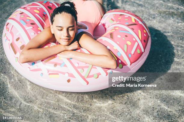 cute girl swimming with a pink inflatable ring at the sea. - tube girl stock-fotos und bilder