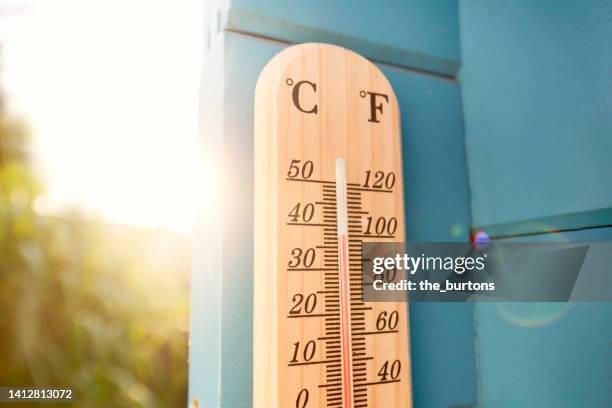 thermometer at blue wooden wall in garden - temperatuur stock-fotos und bilder