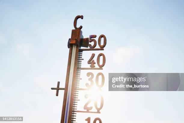 thermometer that indicates 38 degrees celsius against blue sky and sun - celsius photos et images de collection