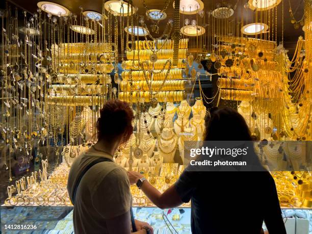 female silhouette in front of gold store display - couple au lit stockfoto's en -beelden