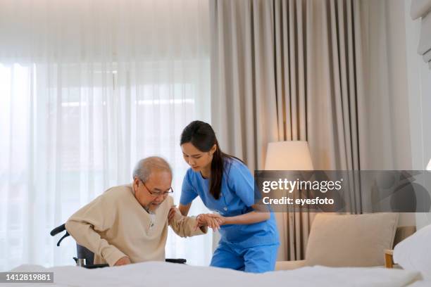 krankenschwester kümmern sich um senior mann im schlafzimmer. - südostasiatischer abstammung stock-fotos und bilder